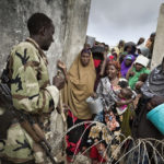 Flüchtlinge versuchen Einlass zur Lebensmittelverteilung zu bekommen. Das Gelände ist überfüllt. Bewaffnete Security Guards der Camp-Verwaltung riegeln die Zugänge ab.