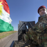 Ein Peschmerga auf einem Pickup unterwegs zur Front bei Mosul. Auf der Ladefläche des Pickups ist ein schweres Maschinengewehr montiert.