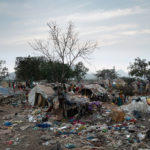 Das Slum der Waste-Picker bei Tagesanbruch. Rund 30 Familien leben hier in unmittelbarer Nähe der stinkenden und unter starker Rauchentwicklung schwelenden Müllkippe in Behausungen aus ausrangierten Wahlplakaten, Pappstücken und Lumpen.